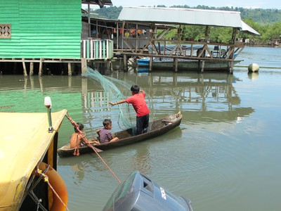 Young boy proficient with the cast net from a boat.