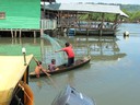 Young boy proficient with the cast net from a boat.